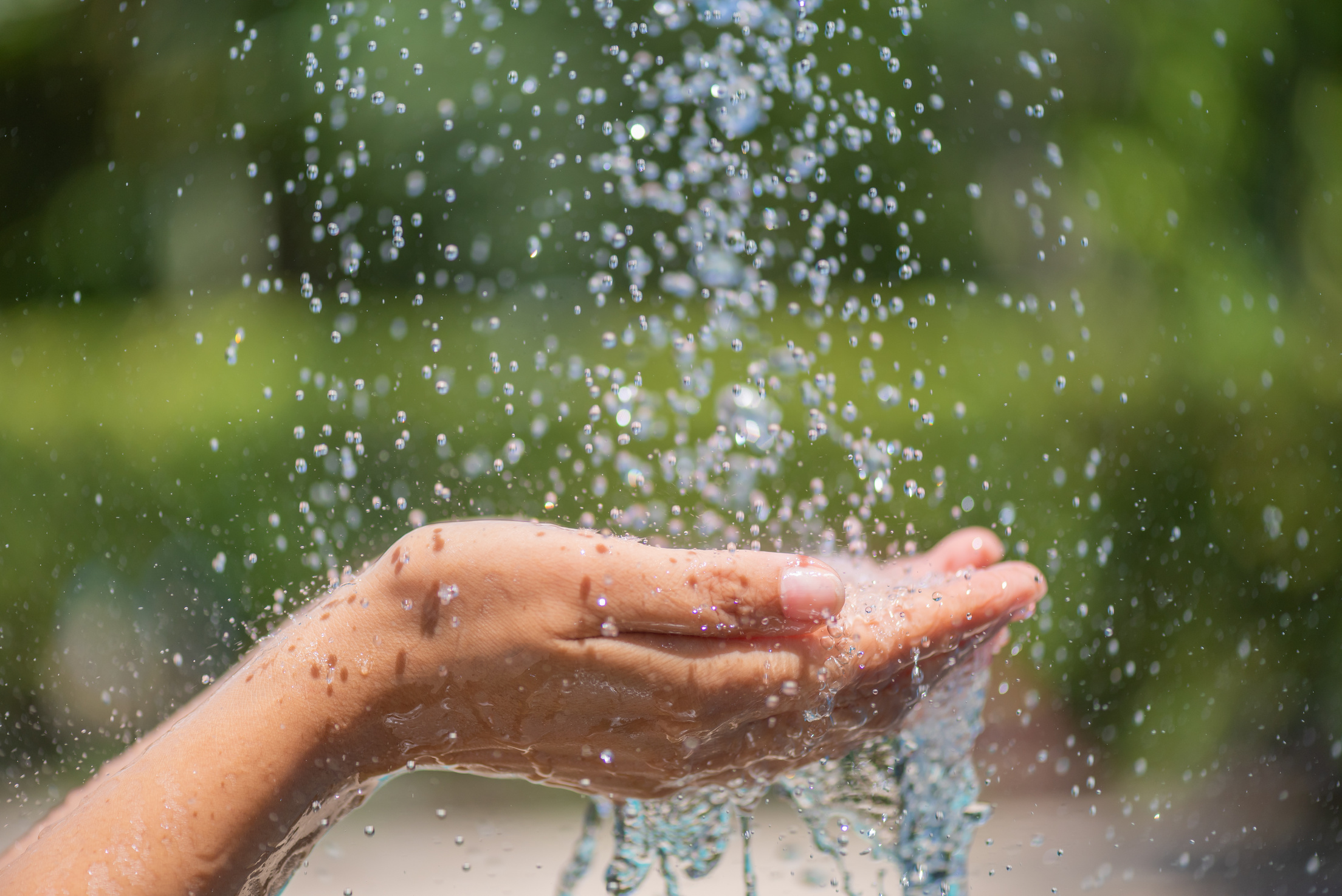 Water pouring in woman's hands. World Water Day concept.